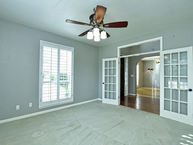 a view of empty room with wooden floor and fan