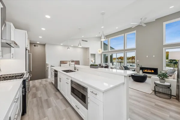a large white kitchen with a stove a sink a refrigerator and a dining table with wooden floor