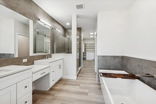a spacious bathroom with a tub sink shower and mirror