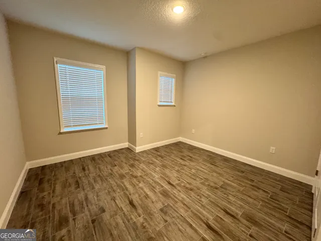 an empty room with wooden floor closet and windows