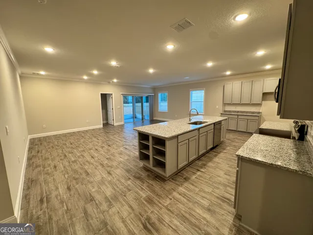 a large kitchen with stainless steel appliances a large counter top a stove a sink and a refrigerator