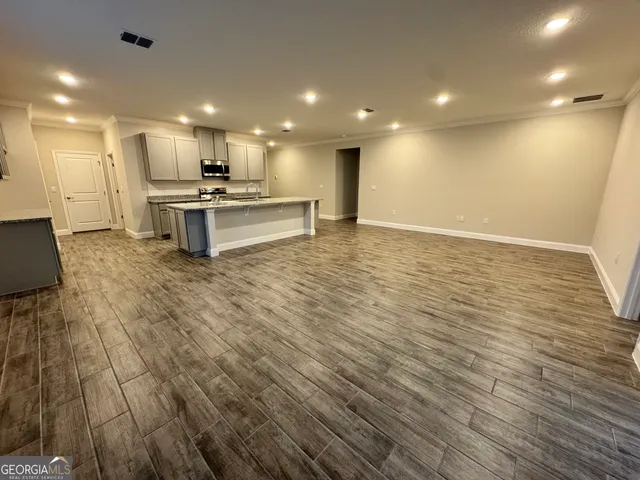 a view of kitchen with kitchen island wooden floor center island and stainless steel appliances