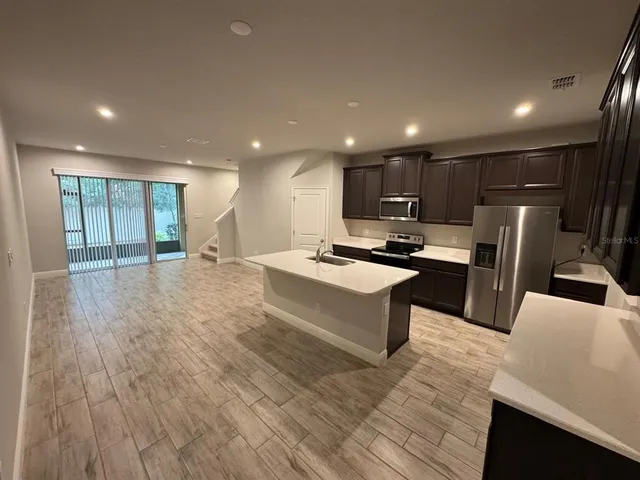 a large kitchen with stainless steel appliances a large counter top a stove and a refrigerator