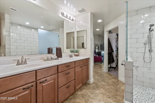 a bathroom with a double vanity sink a large mirror and shower