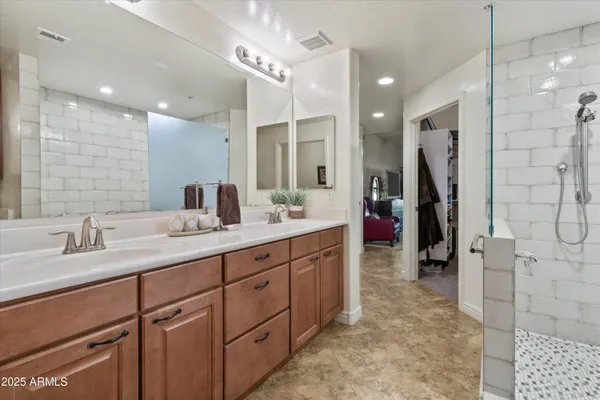 a bathroom with a double vanity sink a large mirror and shower
