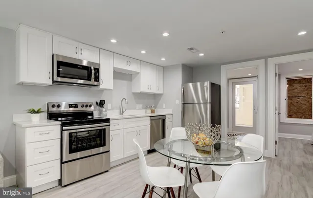 a kitchen with stainless steel appliances granite countertop a stove a sink a microwave a refrigerator and white cabinets