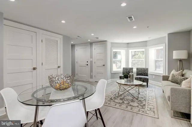 a living room with furniture and a dining table with wooden floor