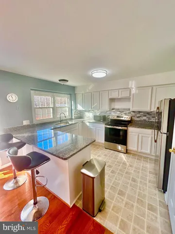 a kitchen with granite countertop a stove a sink a counter space and cabinets