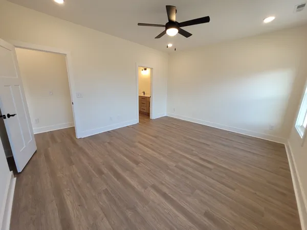 an empty room with wooden floor fan and windows
