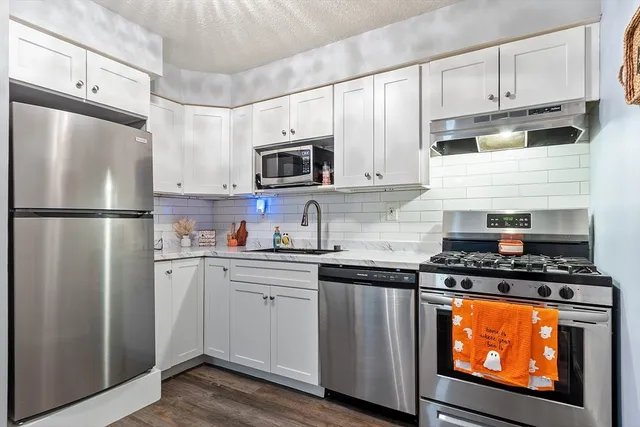 a kitchen with stainless steel appliances granite countertop a refrigerator stove top oven and sink