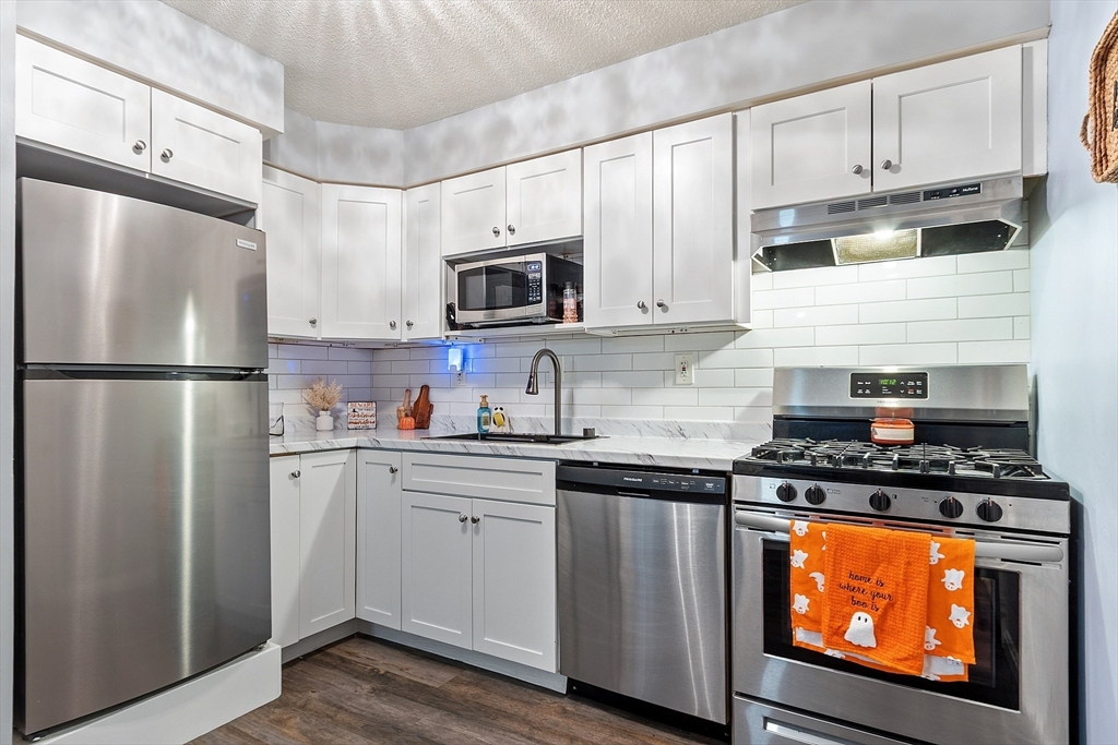 a kitchen with stainless steel appliances granite countertop a refrigerator stove top oven and sink
