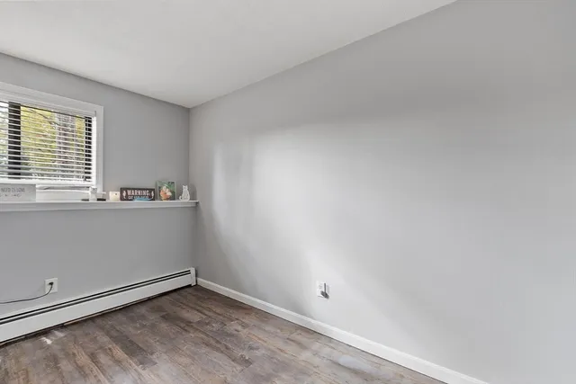 a view of an empty room with wooden floor and window