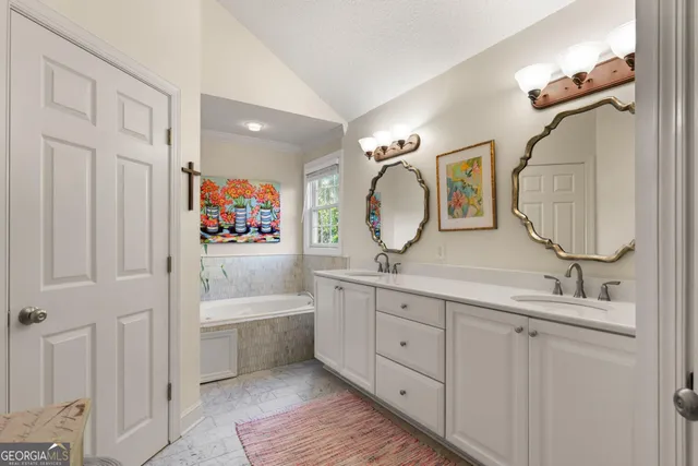 a en suite bathroom with a double vanity sink a mirror a bathtub and shower
