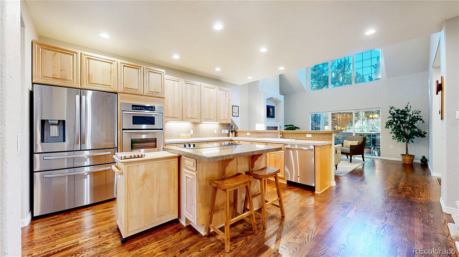 4545 South Monaco Street, Unit 138 Denver, CO 80237 - Photo 6 of 34 a kitchen with stainless steel appliances a refrigerator a stove a sink dishwasher and a dining table with wooden floor