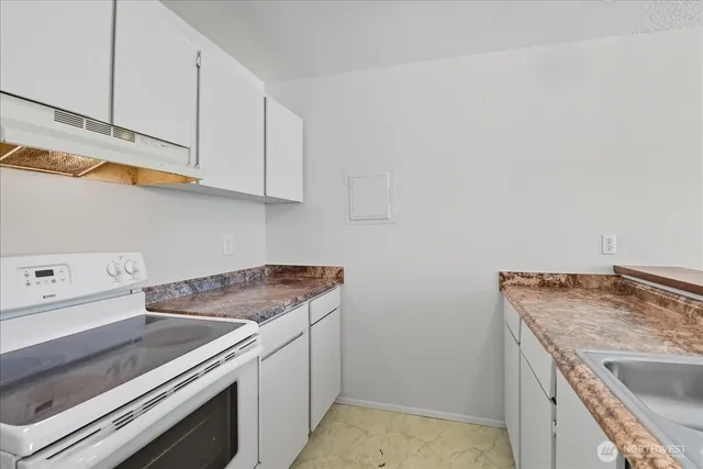 a kitchen with granite countertop a sink a stove and a refrigerator