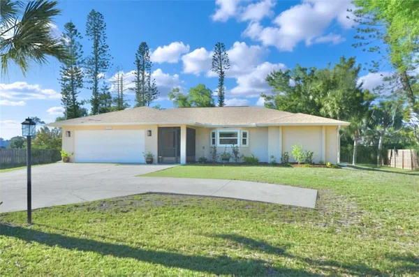 a view of a house with a yard and palm trees