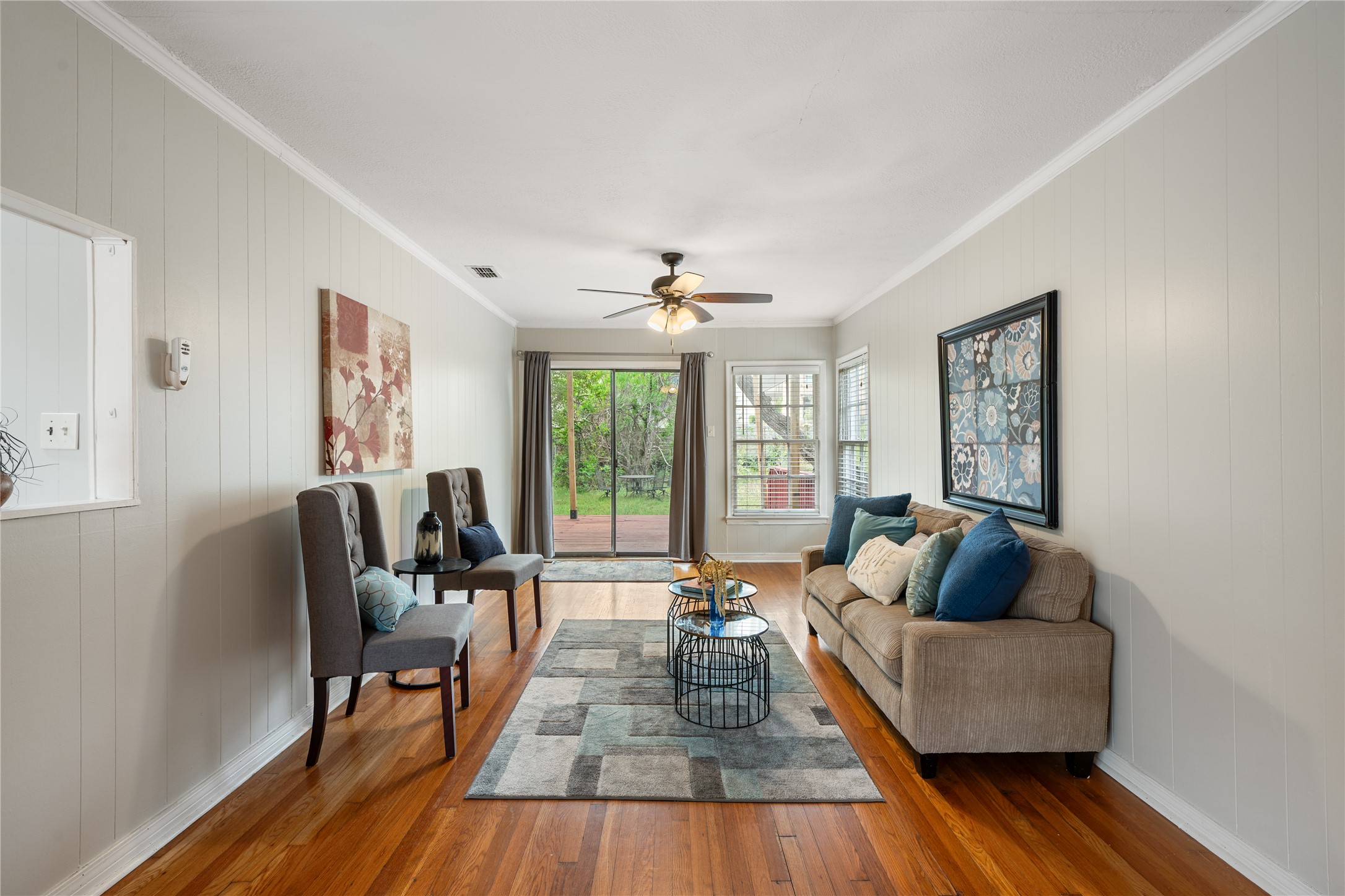 2639 West 45th Street Austin, TX 78731 - Photo 11 of 29 Living room featuring ornamental molding, hardwood / wood-style flooring, wood walls, and a ceiling fan