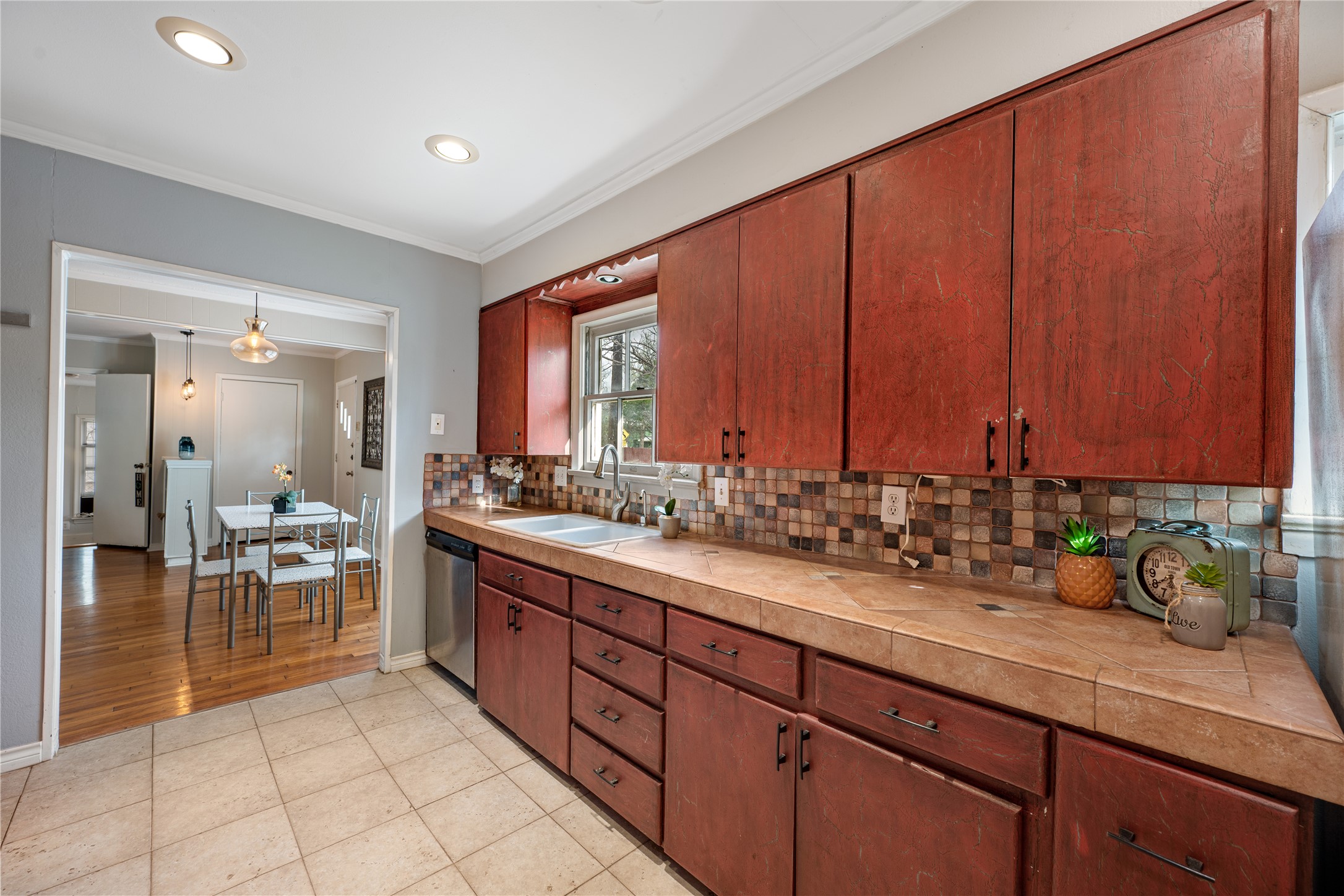 2639 West 45th Street Austin, TX 78731 - Photo 23 of 29 Kitchen featuring light tile patterned floors, crown molding, backsplash, dishwasher, and recessed lighting