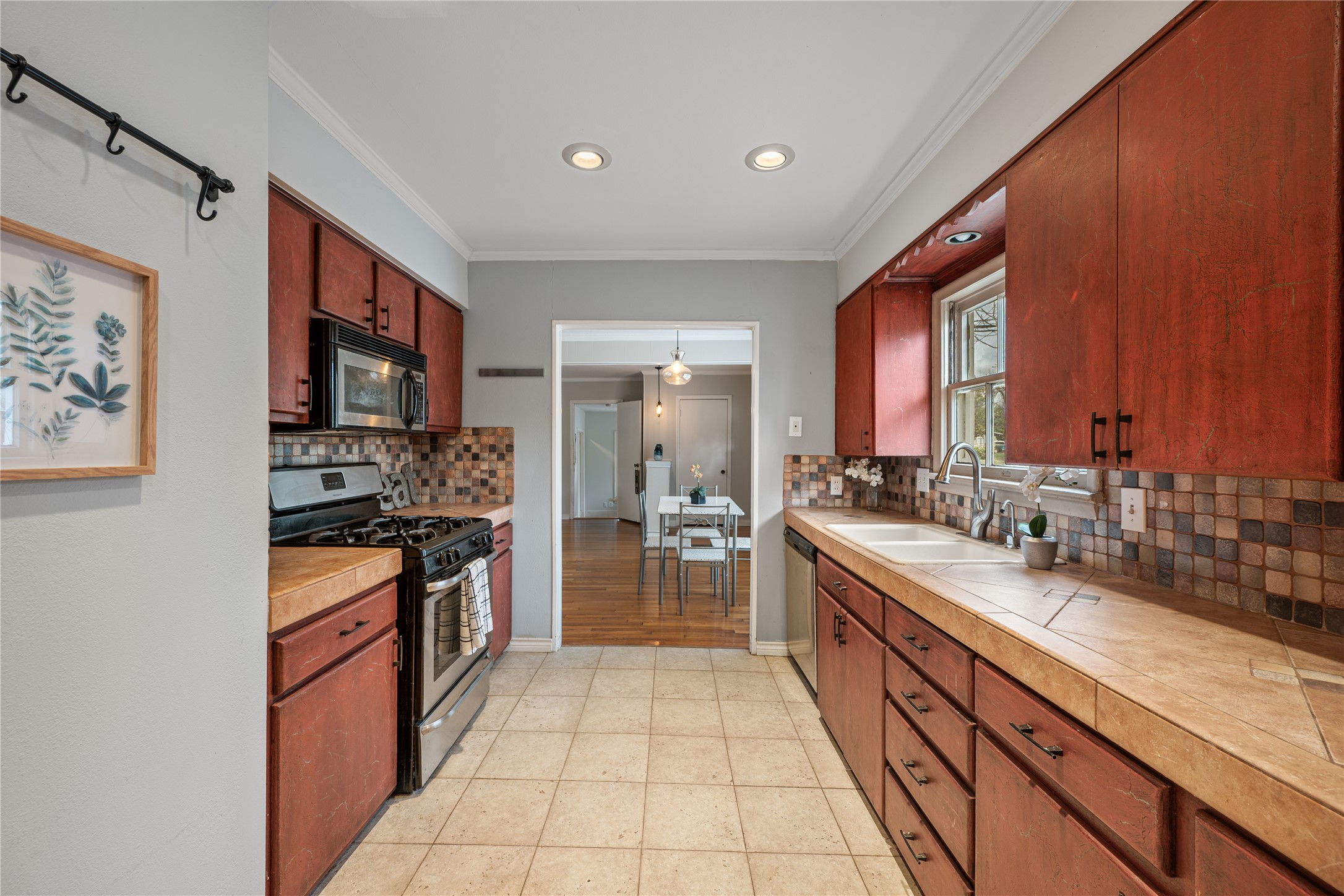 2639 West 45th Street Austin, TX 78731 - Photo 24 of 29 Kitchen featuring stainless steel appliances, crown molding, tasteful backsplash, light tile patterned floors, and tile counters