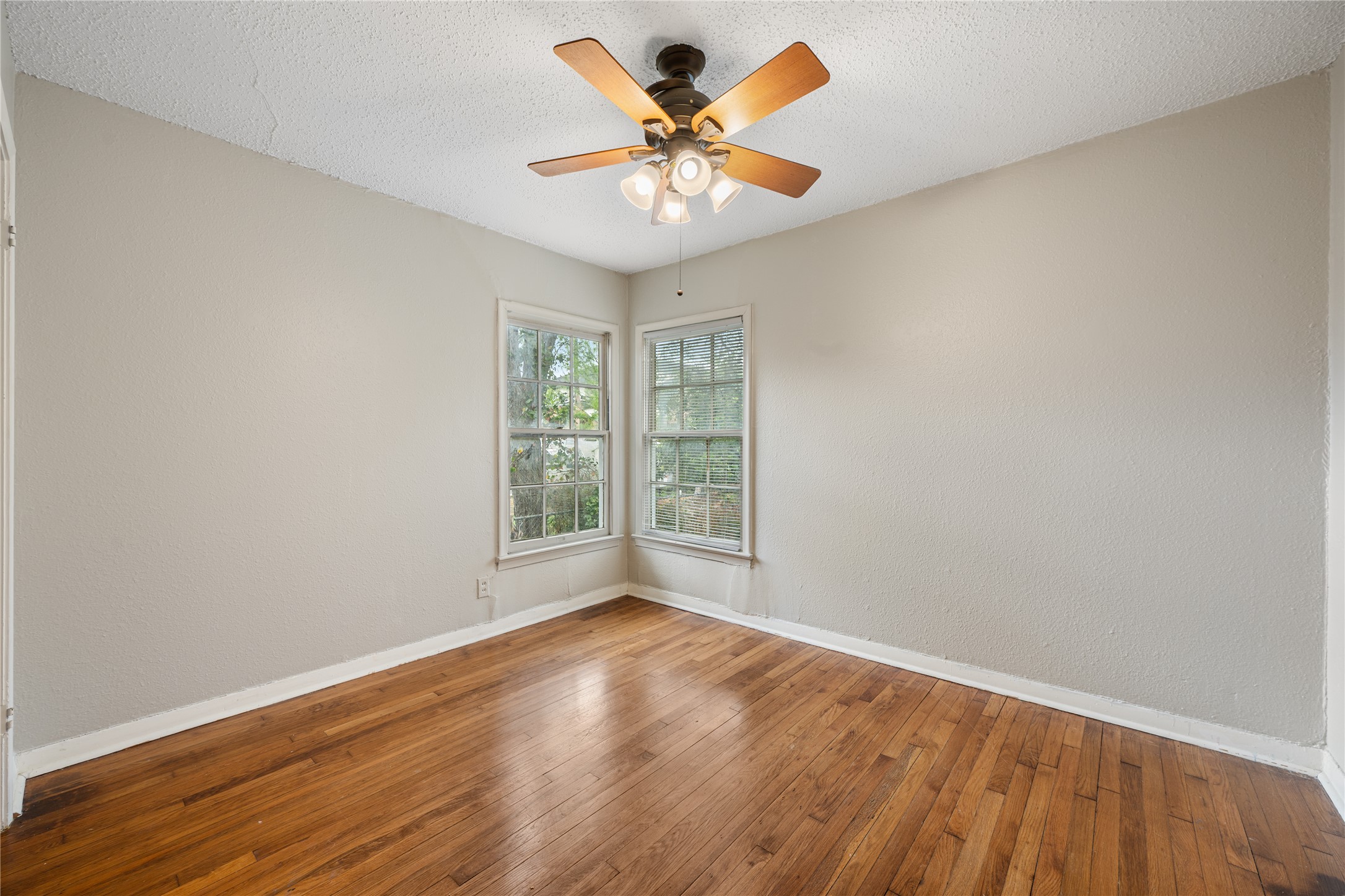 2639 West 45th Street Austin, TX 78731 - Photo 29 of 29 Empty room featuring hardwood / wood-style floors, a textured ceiling, a ceiling fan, and a textured wall