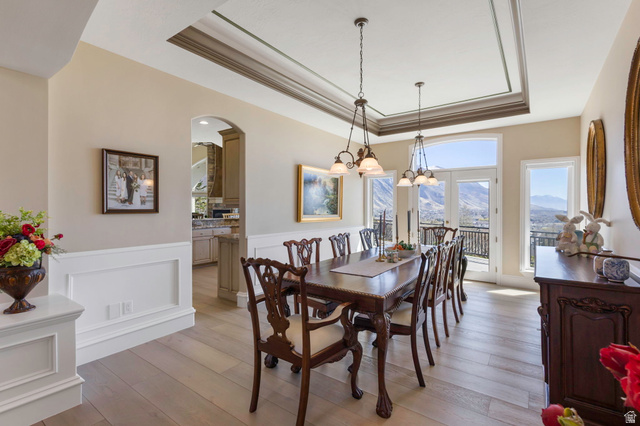 684 North Summit Way Alpine, UT 84004 - Photo 26 of 58 Dining space with a raised ceiling, a mountain view, suspended lighting, arched walkways, and light wood-type flooring