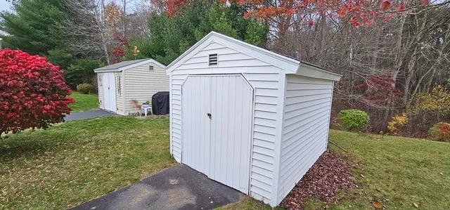 a view of a white house with a small yard and large trees