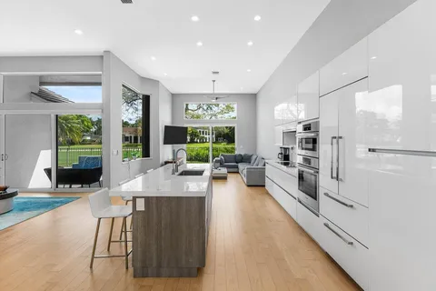 a view of a kitchen with kitchen island a large window cabinets a sink and stainless steel appliances