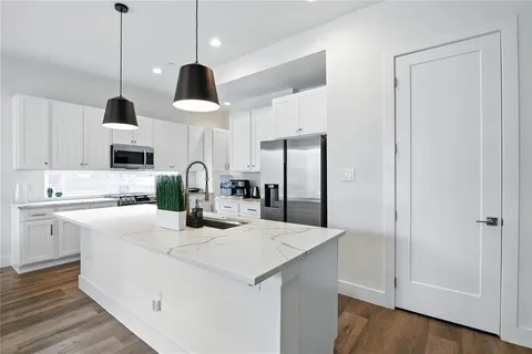 a kitchen with stainless steel appliances granite countertop a sink a stove and a refrigerator