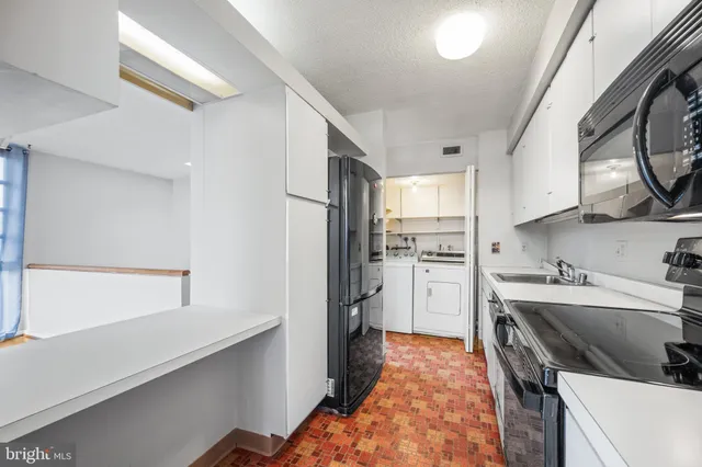 a kitchen with a sink a refrigerator and cabinets