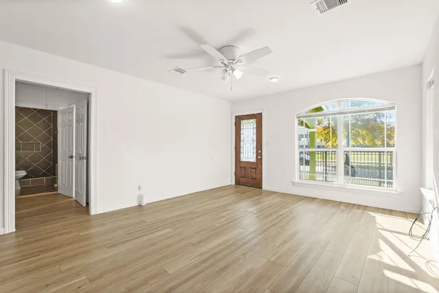 a view of an empty room with a window and wooden floor
