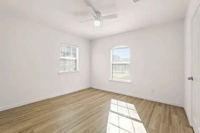 a view of an empty room with wooden floor and a window
