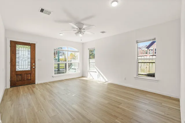 a view of an empty room with a window and wooden floor