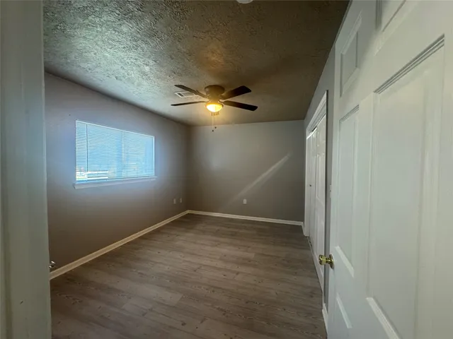 an empty room with wooden floor and fan