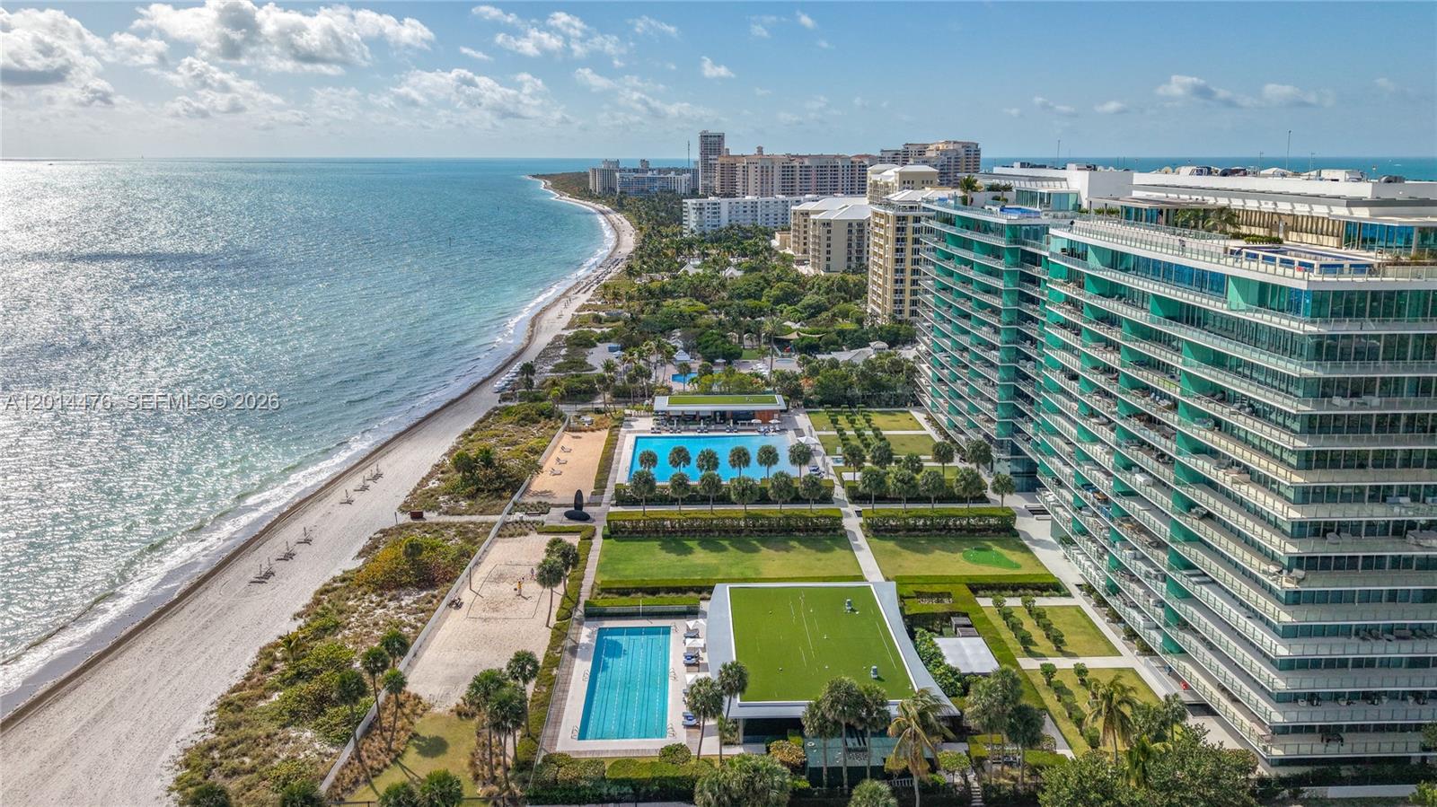 360 Ocean Drive, Unit 1106S Key Biscayne, FL 33149 - Photo 42 of 67 Aerial Coastline View – This aerial perspective highlights the building’s placement along the shoreline, with beach access, pools, and landscaped amenity areas visible below. The coastline stretches into the distance for a dramatic waterfront backdrop.