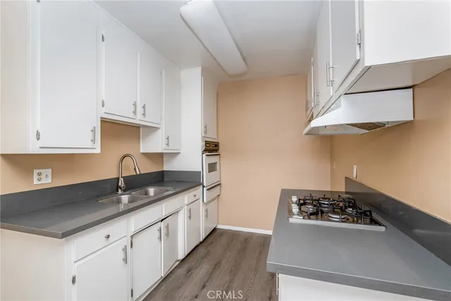 a kitchen with stainless steel appliances a sink a stove and white cabinets