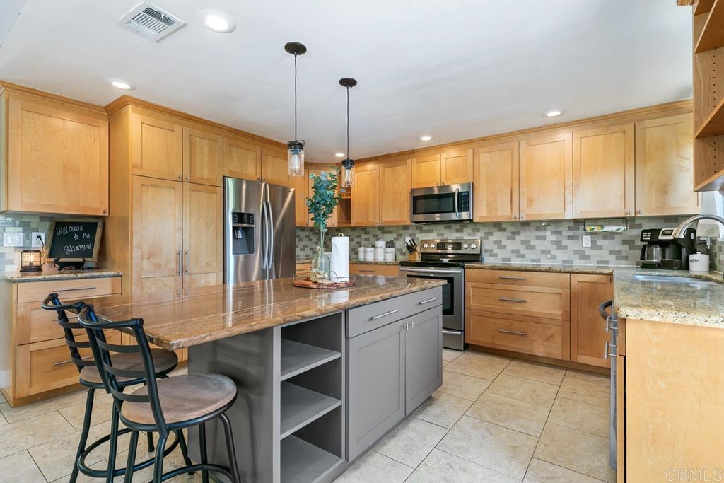 1005 Woodcreek Road Fallbrook, CA 92028 - Photo 12 of 32 a kitchen with stainless steel appliances granite countertop a stove a sink a microwave oven with a dining table and chairs