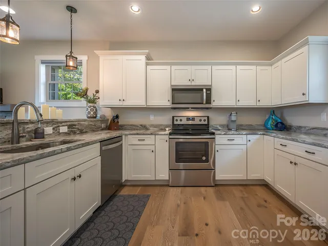 a kitchen with stainless steel appliances granite countertop a sink a stove and cabinets