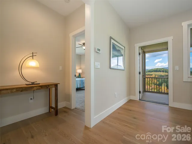 a view of an empty room with a window and wooden floor