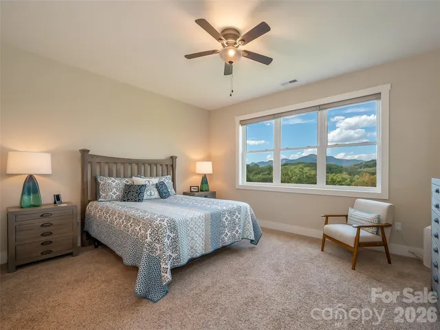 a spacious bedroom with a bed a chandelier and a large window