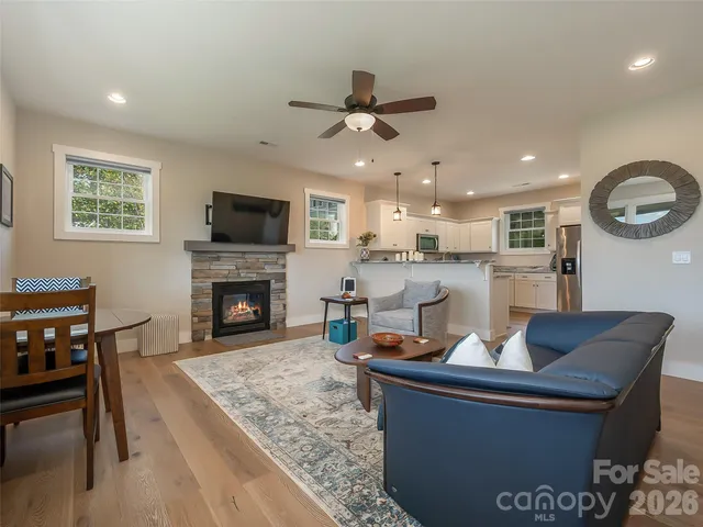 a living room with a fireplace a flat screen tv and kitchen view