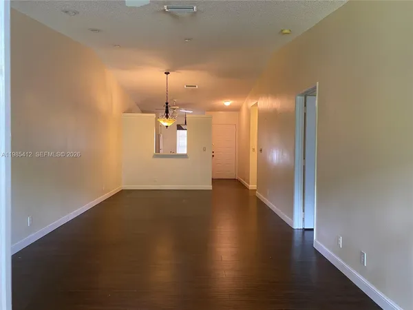 an empty room with wooden floor mirror and windows