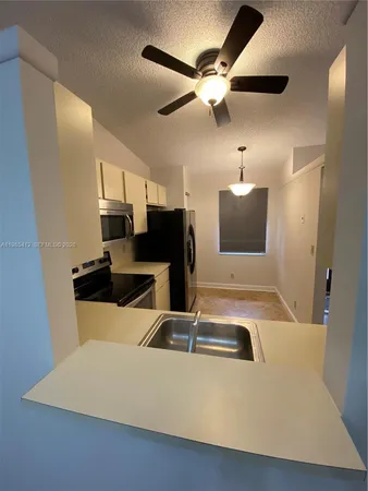 a view of kitchen with a sink and refrigerator
