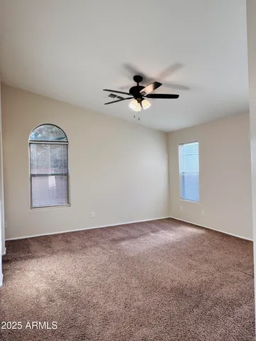 an empty room with windows and ceiling fan