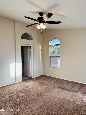an empty room with windows and fan