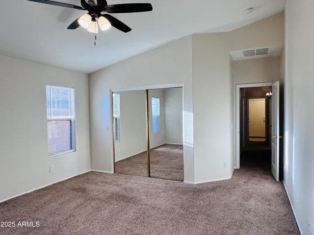 an empty room that has a mirror and a ceiling fan