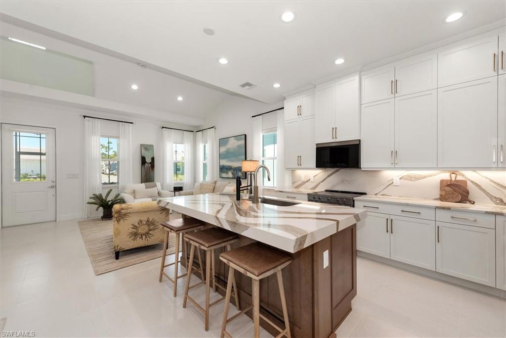 7315 Cayo Coco Lane Naples, FL 34113 - Photo 11 of 30 a open kitchen with kitchen island a sink white cabinets and chairs