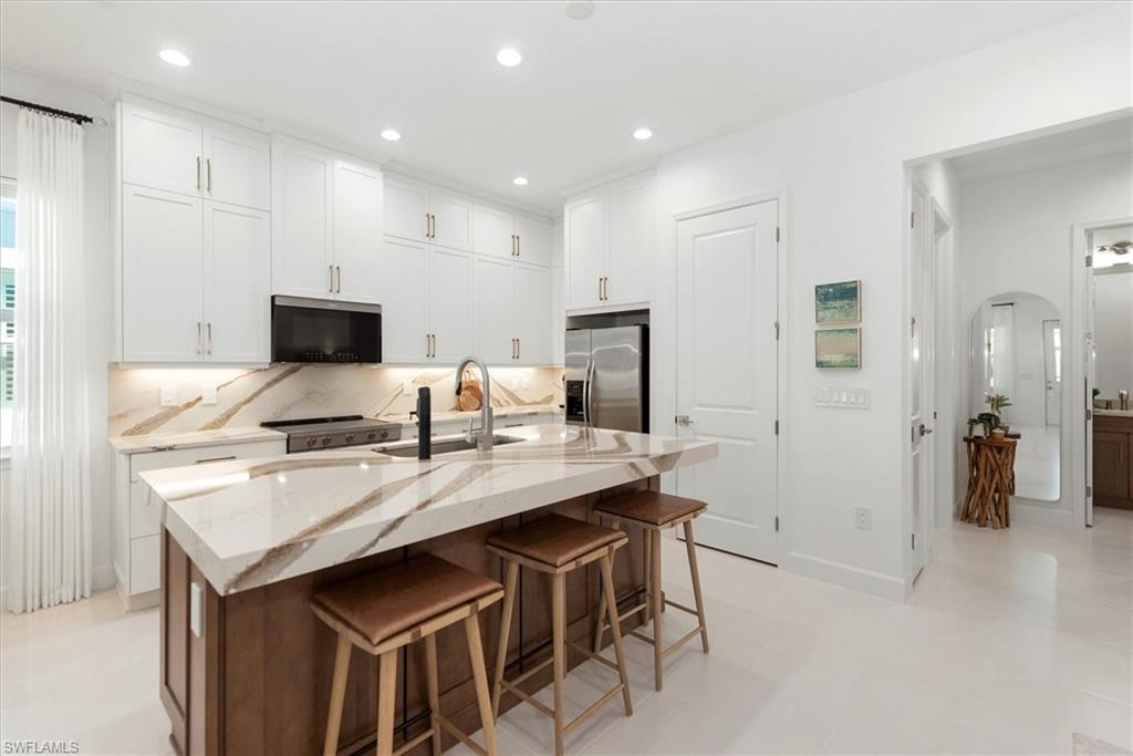 7315 Cayo Coco Lane Naples, FL 34113 - Photo 8 of 30 a kitchen with a sink a microwave a refrigerator and white cabinets