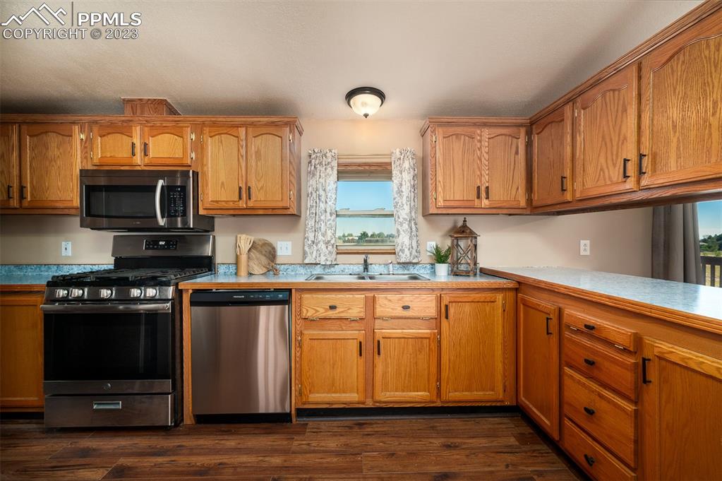 5695 Peerless Farms Road Peyton, CO 80831 - Photo 19 of 50 a kitchen with stainless steel appliances granite countertop a stove a sink and a microwave