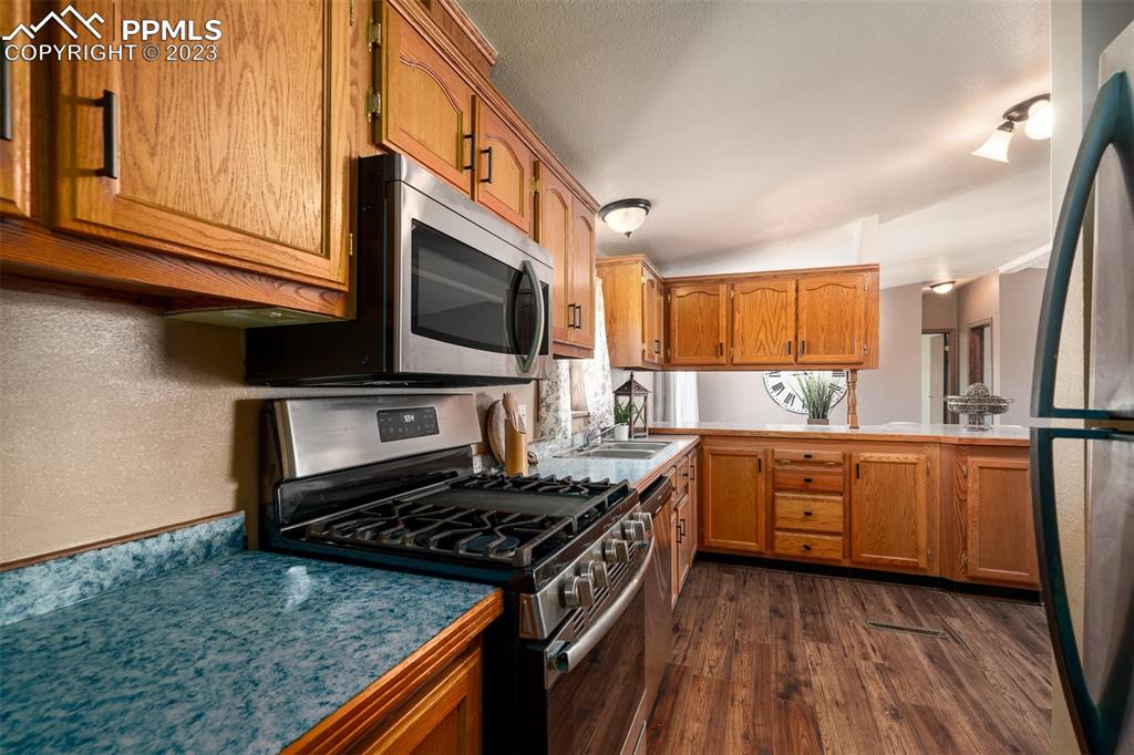 5695 Peerless Farms Road Peyton, CO 80831 - Photo 21 of 50 a kitchen with stainless steel appliances granite countertop a stove a sink and a microwave