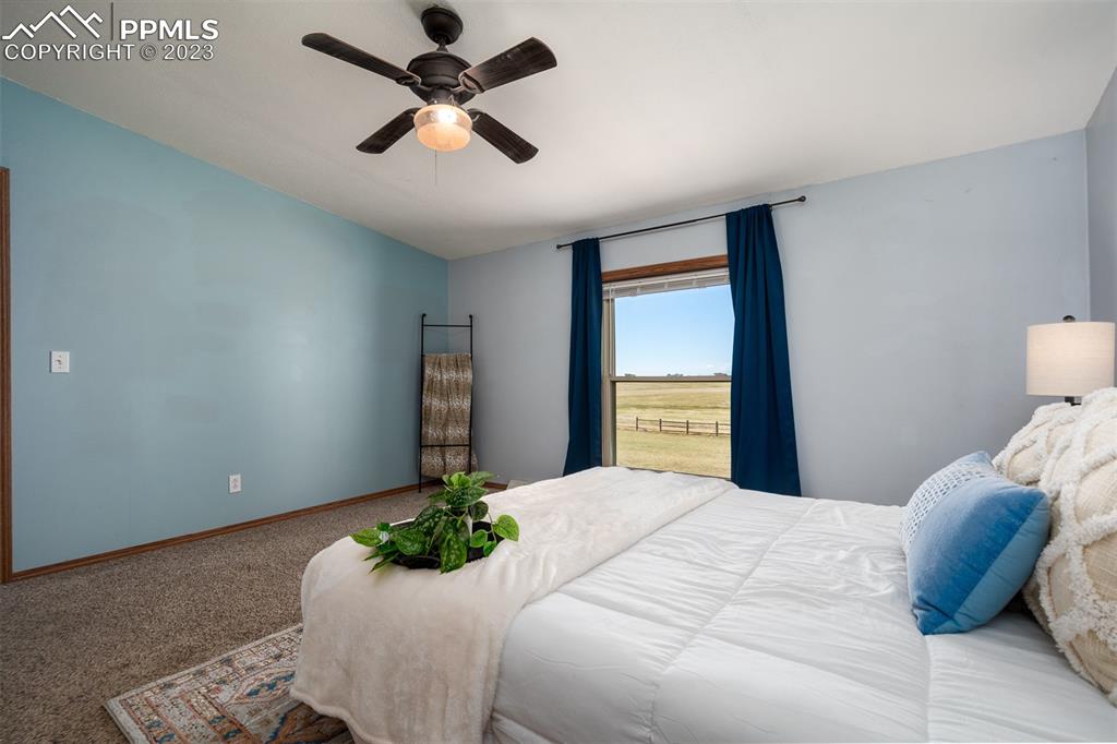 5695 Peerless Farms Road Peyton, CO 80831 - Photo 25 of 50 a bedroom with a bed and a ceiling fan